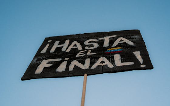 Close-up of a protest sign saying "Hasta el Final" against a clear blue sky.