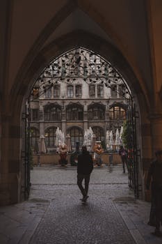Silhouette walking through archway into a historic courtyard in central Munich, Germany.