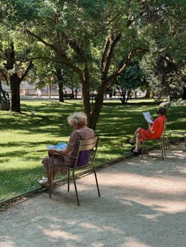Two women enjoying a peaceful reading session in the lush Luxembourg Gardens, Paris.